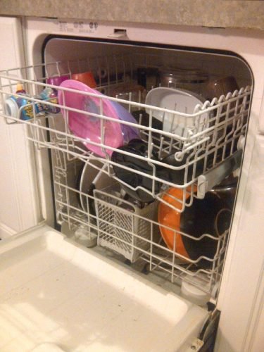A fully loaded dishwasher filled with various dishes, pots, and pans in a Charleston kitchen, demonstrating proper loading techniques.