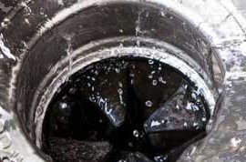 Detailed view of a black pipe discharging water in a Charleston home, highlighting essential tips for avoiding garbage disposal clogs.