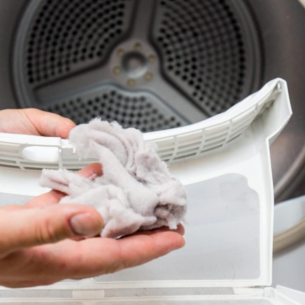 A person holds a piece of cloth in front of an LG dryer in a Charleston home, indicating a no heat issue during laundry.