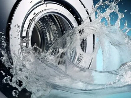 Water splashes from a washing machine in a Charleston home, highlighting a problem with drainage that requires fixing.