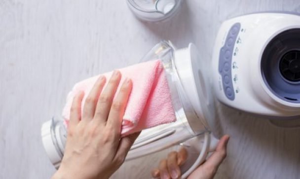 An individual cleaning a blender with a pink cloth in a Charleston home, showcasing effective blender cleaning tips.