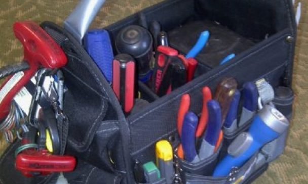 A tool bag with assorted tools resting on the floor of a home in Charleston, serving as a reminder for appliance inspection steps.