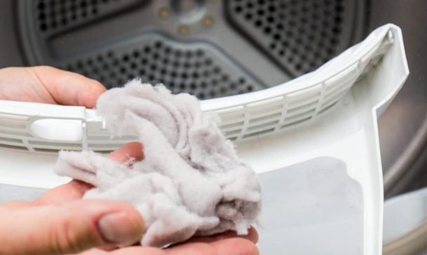A person holds a piece of cloth in front of an LG dryer in a Charleston home, indicating a no heat issue during laundry.